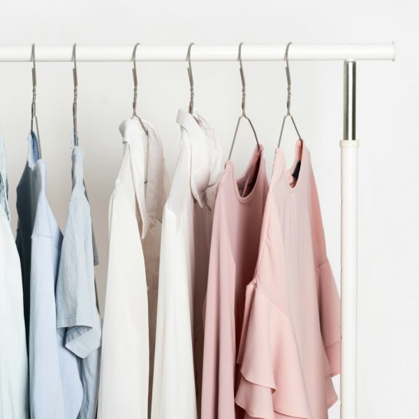 Women's casual clothes in soft pastel colors on a gray metal hanger on a stand, hanger